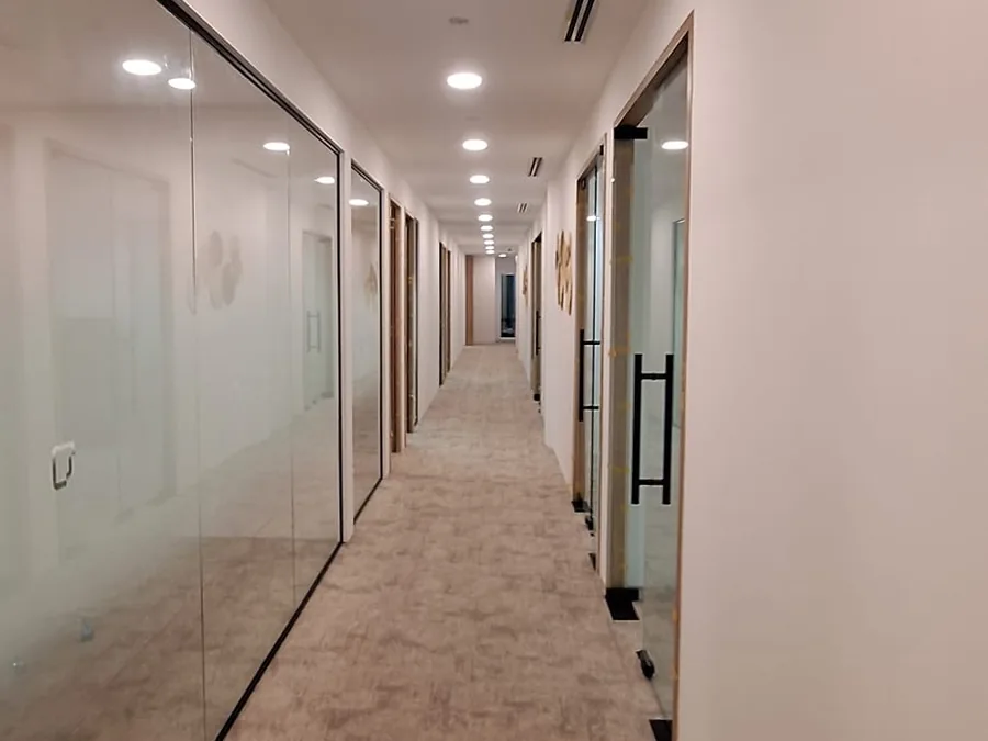 Bright office corridor lined with glass-fronted rooms